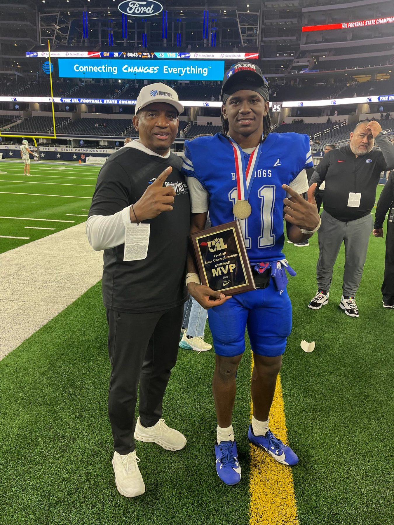 X'Zavier Barnett holding the MVP plaque on the field with a coach