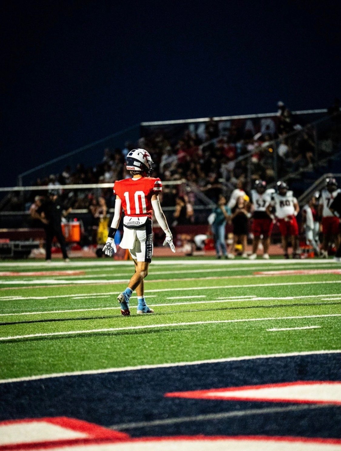 Trinity Lions receiver walking to the line under the lights, DigiWrist on the wrist